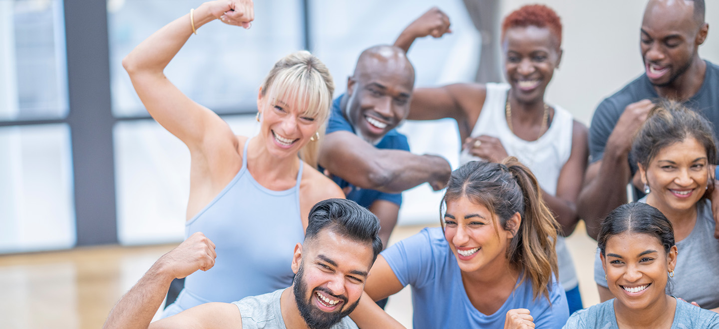 Image of a group of people working out and flexing while smiling at the camera