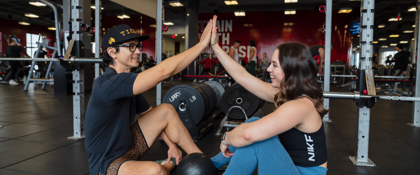 a man and a woman high fiving in the gym after a workout